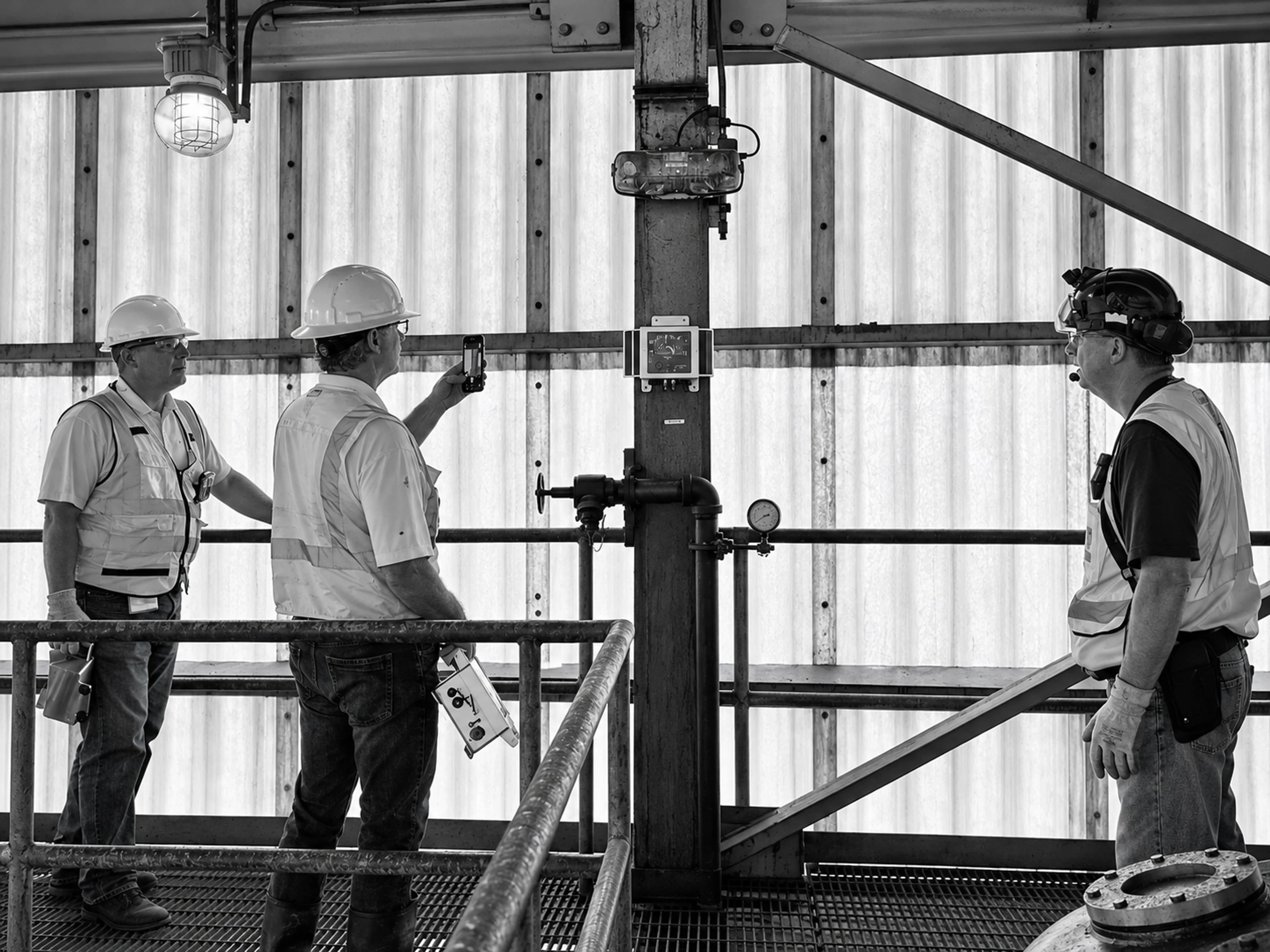 Structural engineers inspect monitoring equipment mounted on a steel column inside a building.